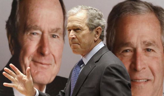 Former President George W. Bush passes by a portrait of himself and his father former President George H.W. Bush as he takes the stage to discuss his new book, "41: A Portrait of My Father" at the his father's presidential library Tuesday, Nov. 11, 2014, in College Station, Texas. (Associated Press) 